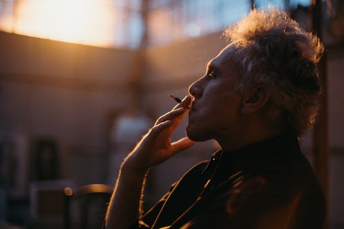 一个男人穿着黑衬衫抽烟的侧视图 · 免费素材图片