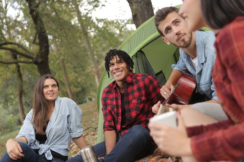 快乐的多民族朋友在公园与吉他一起休息 · 免费素材图片