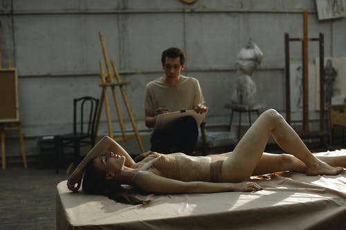 男子手持纸板附近躺在床上的女人 · 免费素材图片