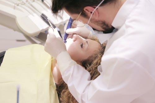 男牙医在女人的牙齿上工作 · 免费素材图片
