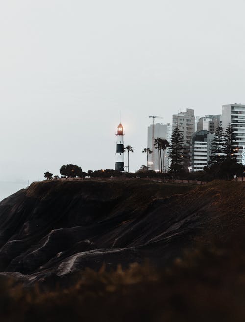 悬崖附近的白色和黑色灯塔 · 免费素材图片