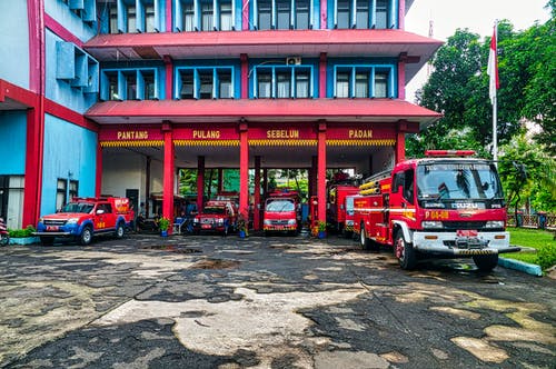 消防车停在蓝色和红色的建筑物上 · 免费素材图片
