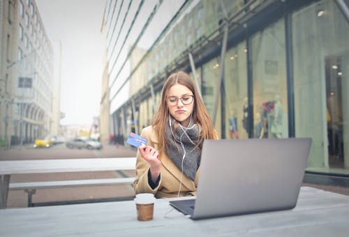 拿着银行卡的棕色外套的女人 · 免费素材图片