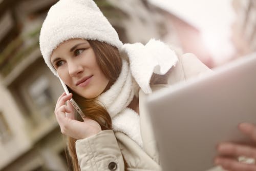 白色帽子和白色围巾使用智能手机的女人 · 免费素材图片