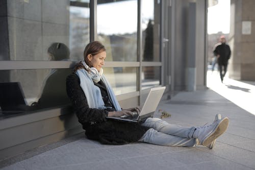 黑色外套和灰色的裤子，坐在灰色的水泥地板上的女人 · 免费素材图片
