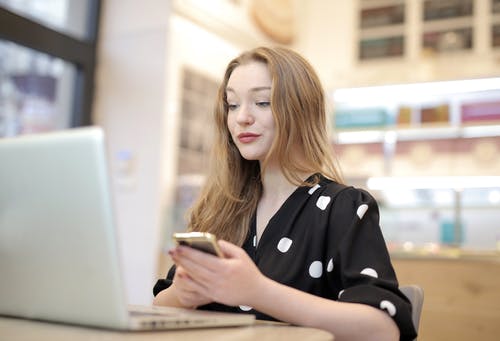 黑色和白色波尔卡圆点裙使用便携式计算机的女人 · 免费素材图片