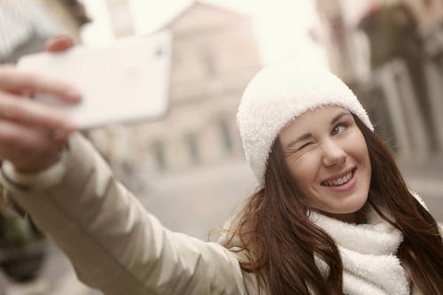 一名旅游妇女穿着白色针织帽以自拍照 · 免费素材图片