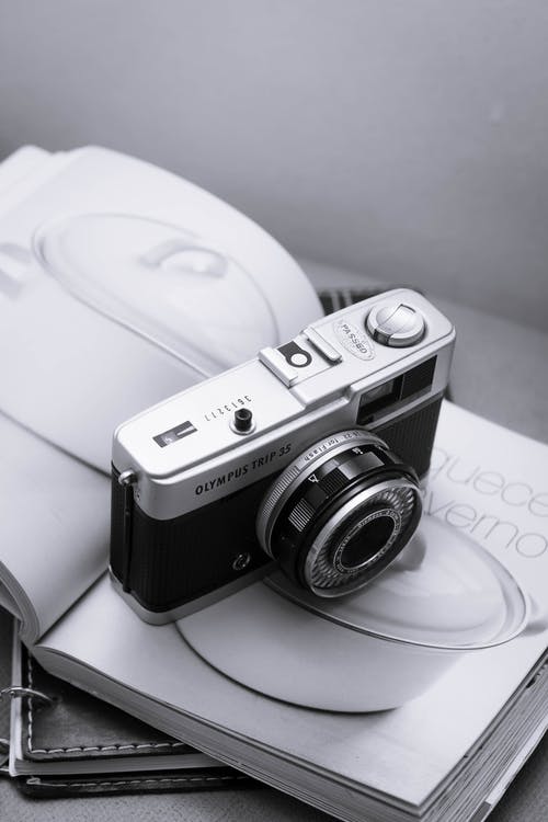 白色杂志上的黑色和银色相机 · 免费素材图片