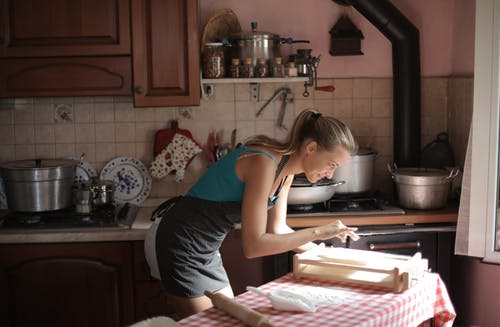 蓝色无袖衫站在厨房柜台附近的女人 · 免费素材图片