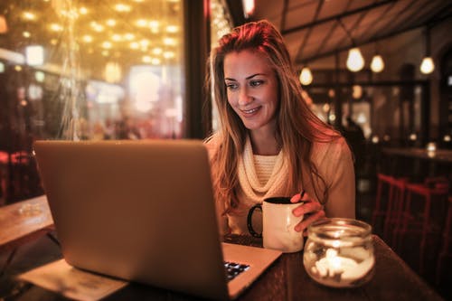 女人坐在桌旁，使用银色笔记本电脑 · 免费素材图片