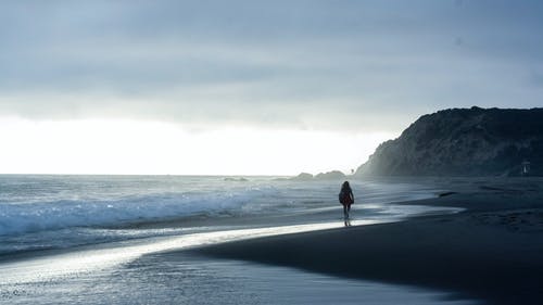 一个女人在海边散步的剪影照片 · 免费素材图片