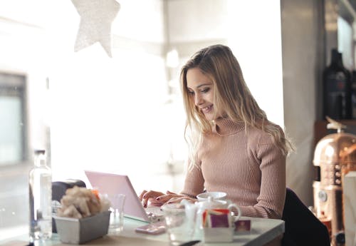 棕色长袖使用一台笔记本电脑的女人 · 免费素材图片