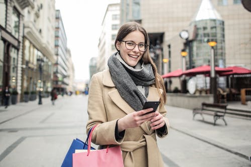 拿着智能手机的棕色外套的女人 · 免费素材图片