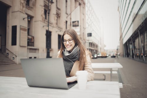 棕色外套使用一台笔记本电脑的女人 · 免费素材图片