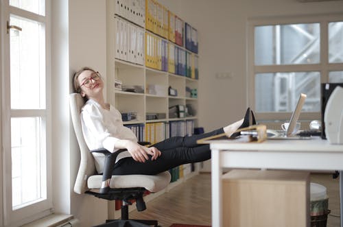 轻松的女秘书，脚在桌上的工作场所 · 免费素材图片