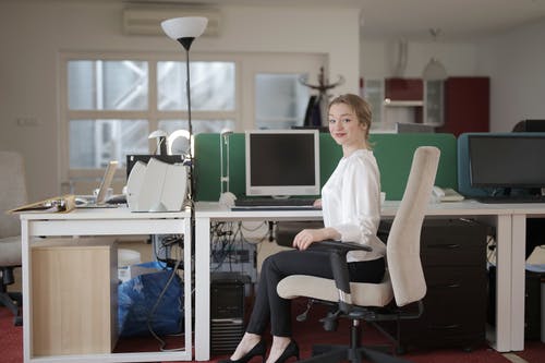 优雅的女雇员，坐在椅子上在现代工作场所 · 免费素材图片
