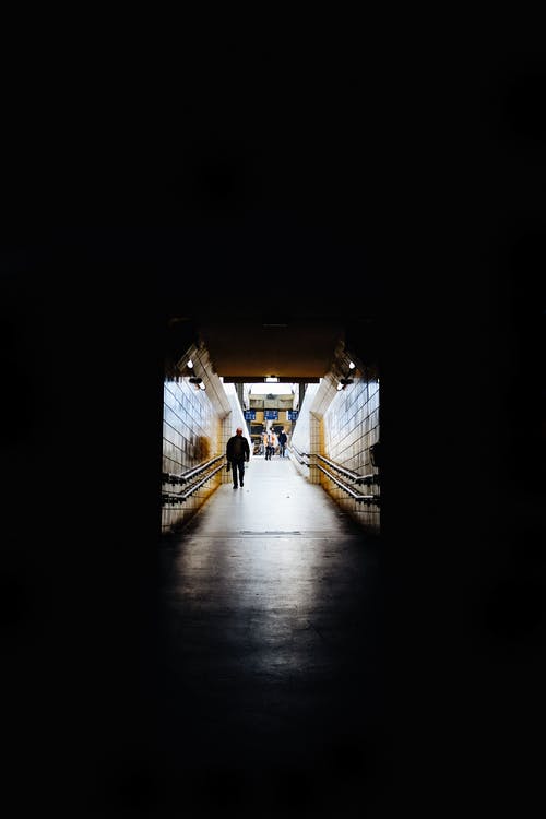 在黑暗的隧道中行走的人的照片 · 免费素材图片