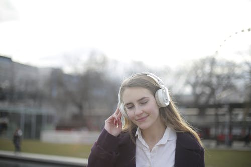 女人戴着白色耳机的浅焦点照片 · 免费素材图片