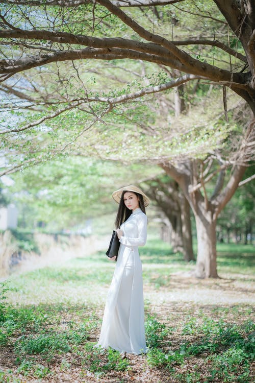 站在棕色树下的白色长袖连衣裙的女人 · 免费素材图片