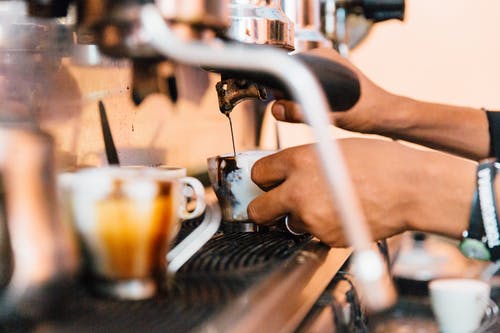 匿名员工从自助餐厅里的机器倒咖啡 · 免费素材图片