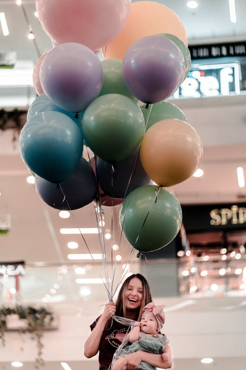 女人抱着五颜六色的气球和她的孩子 · 免费素材图片