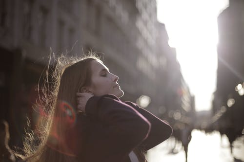 固定她的头发时穿紫大衣的女人 · 免费素材图片