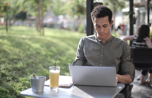 集中在街头咖啡馆中使用笔记本电脑的黑人男性自由职业者 · 免费素材图片
