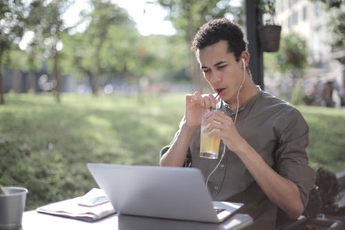 黑人在咖啡馆喝柠檬水和使用笔记本电脑 · 免费素材图片