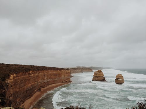 在灰色的天空下海上的棕色岩层 · 免费素材图片