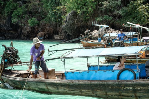 漂浮在河上的船上钓鱼的面目全非的人 · 免费素材图片