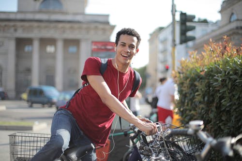 男人穿着红色衬衫站在自行车上 · 免费素材图片