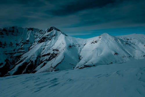 多云的天空下的积雪的山 · 免费素材图片