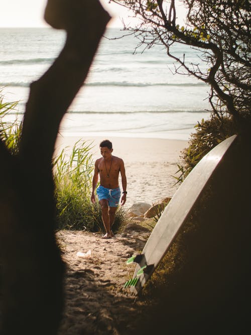 蓝色牛仔短裤的女人坐在水边附近的棕色木原木上 · 免费素材图片