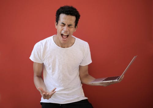 与笔记本电脑尖叫的年轻族裔男性 · 免费素材图片