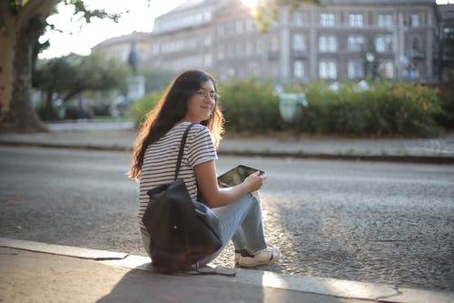 坐在人行道上的黑色和白色条纹衬衫的女人 · 免费素材图片