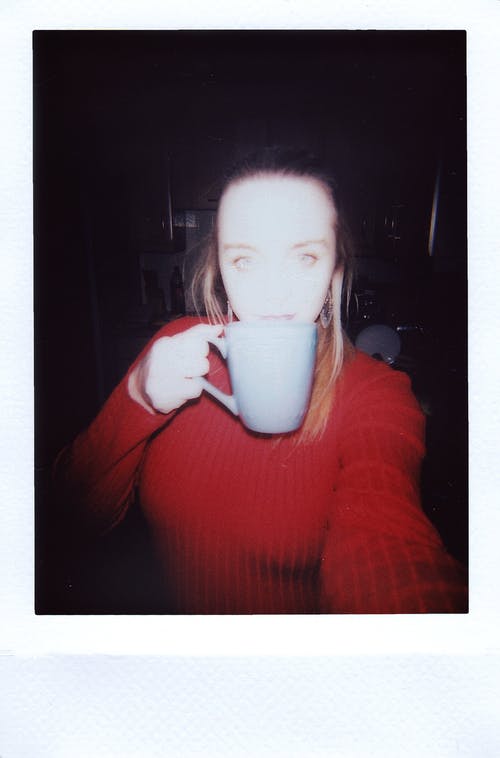 从白色陶瓷杯喝的红色毛衣的女人 · 免费素材图片