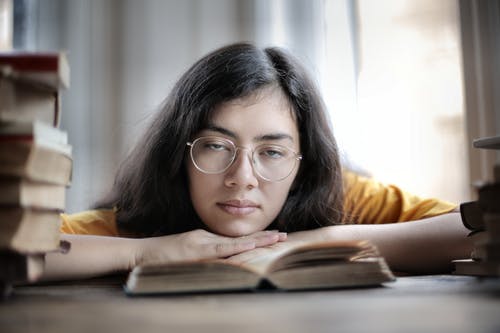 说谎在书的疲乏的女学生在图书馆里 · 免费素材图片