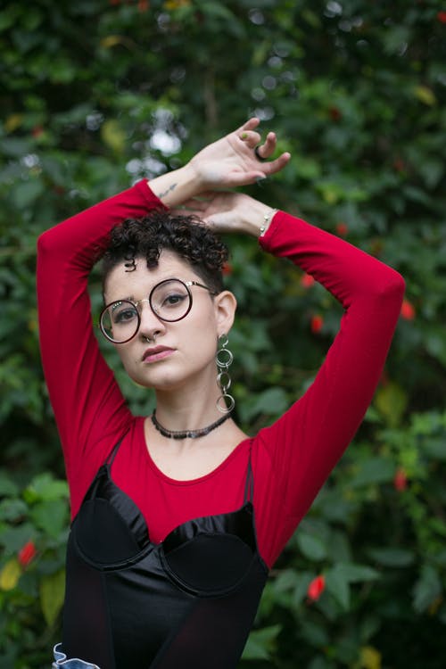 女人举起手臂时戴着黑色镜框的眼镜 · 免费素材图片