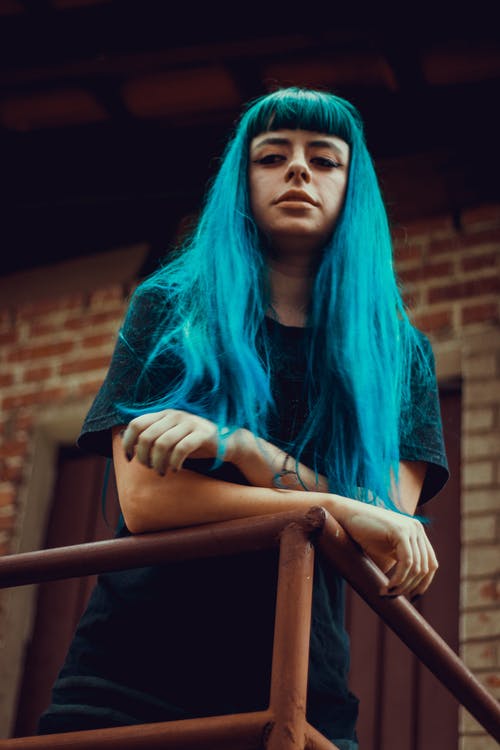 靠在金属栏杆上的蓝色头发的女人 · 免费素材图片