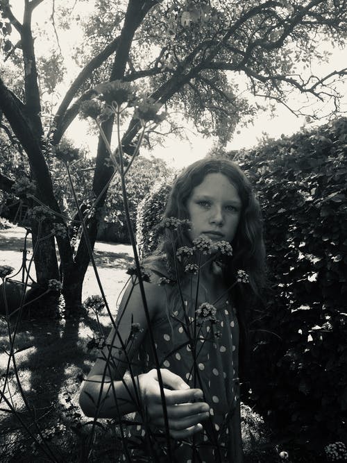 女人站在开花植物附近的单色照片 · 免费素材图片