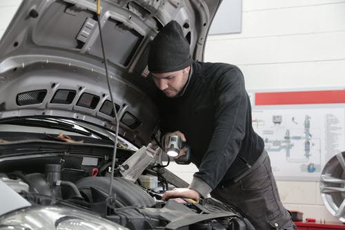 黑色外套和黑色针织帽的人检查汽车发动机 · 免费素材图片