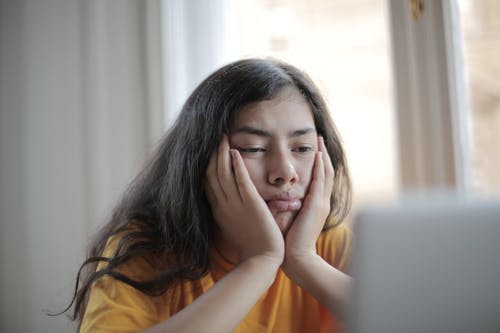 忧郁的女人在家里的笔记本电脑上观看视频 · 免费素材图片