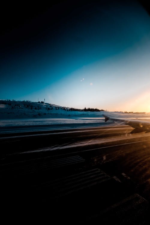 日落时在白雪皑皑的地形上的飞机场 · 免费素材图片