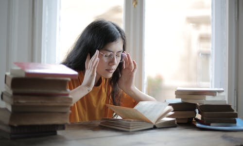 女学生患有头痛在图书馆 · 免费素材图片