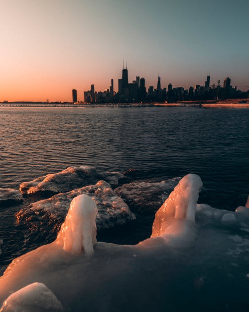 冰冷的岩石与日落的城市天际线 · 免费素材图片