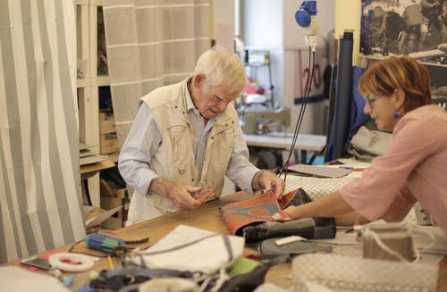老年工匠与助手在车间制作皮包 · 免费素材图片
