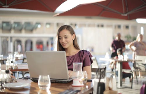 紫色衬衫坐在桌旁使用macbook的女人 · 免费素材图片