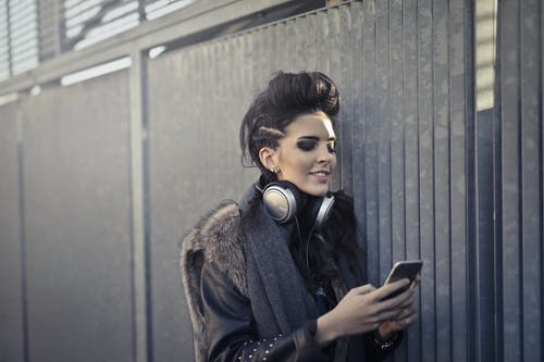 黑色和棕色皮大衣，戴着黑色耳机的女人 · 免费素材图片