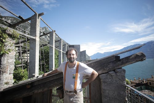 穿着白色圆领t恤的男人站在木制棚子附近 · 免费素材图片