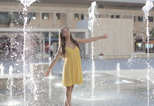 黄色无袖连衣裙站在喷泉上的女人 · 免费素材图片